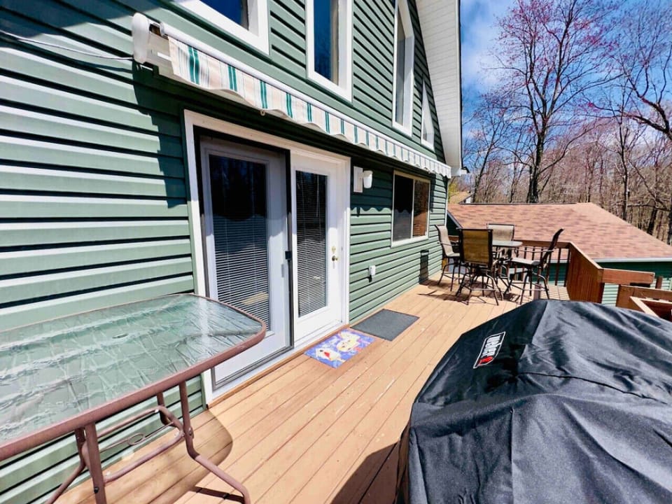 Upper deck in backyard with grill and seating for 4 at high top table.