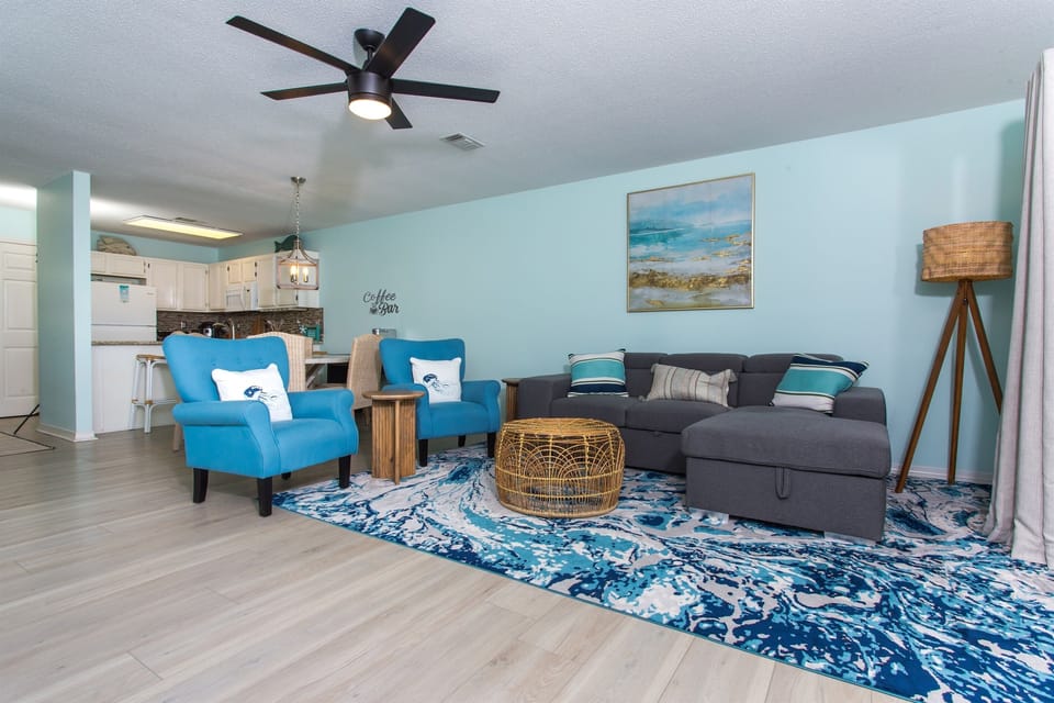 This open space living room and kitchen in a beach house exemplifies the perfect blend of functionality, comfort, and coastal charm