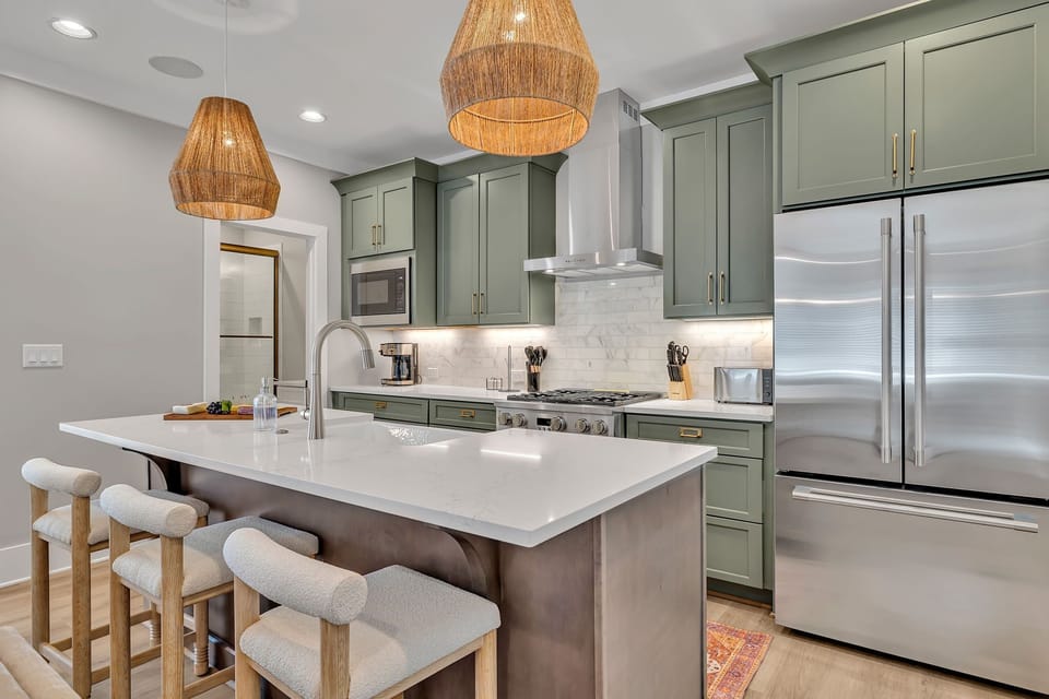 2nd Floor: Fully equipped kitchen stocked with all culinary essentials featuring stainless-steel appliances and a kitchen island offering ample counter space and bar seating.