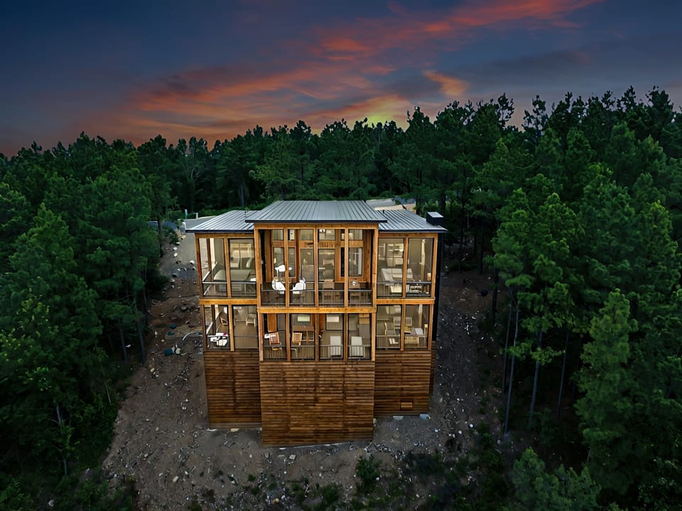 Two spacious back decks offer everything you need for outdoor living, including dining space, lounge chairs, a hot tub, barrel sauna, propane fireplaces, TVs, and cozy swing chairs—all surrounded by stunning mountain views.