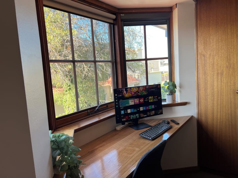 Dedicated work area with 27" smart monitor, keyboard & mouse. Leafy outlook.