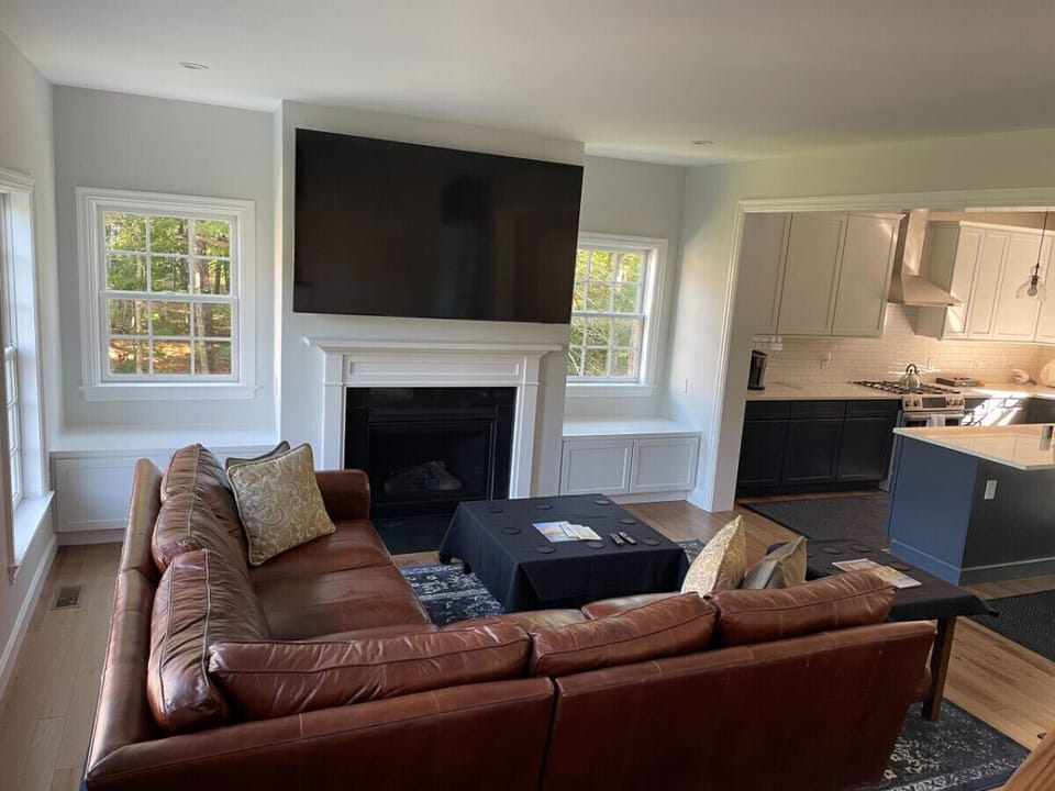 Den area with a beautiful leather couch and an 85` TV