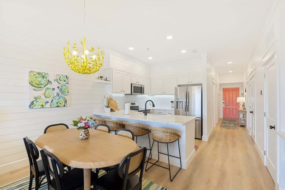 - Cheerful dining nook flows into the fully equipped kitchen with bar seating for four - White shiplap walls, bold lighting, and modern appliances bring function and fun together - Perfect for cooking, gathering, or unwinding after a beach day