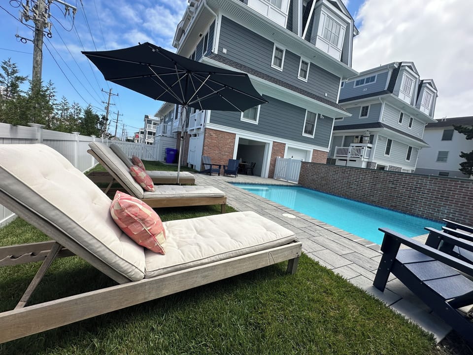 3 lounge chairs, large umbrella, 4 outdoor chairs around pool