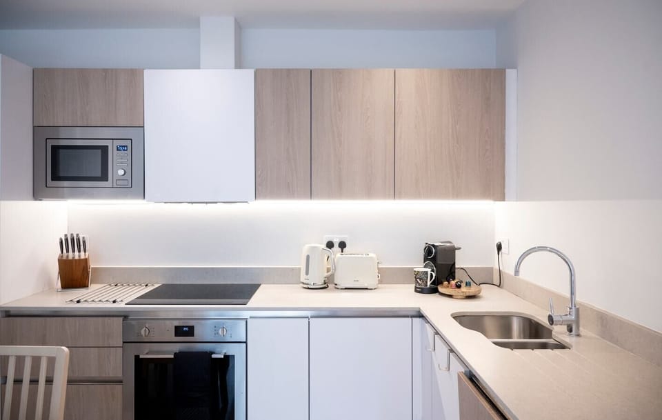 The fully equipped kitchen has an oven and induction hob, microwave, kettle, toaster, dishwasher, Nespresso machine, and a dining table with four chairs.