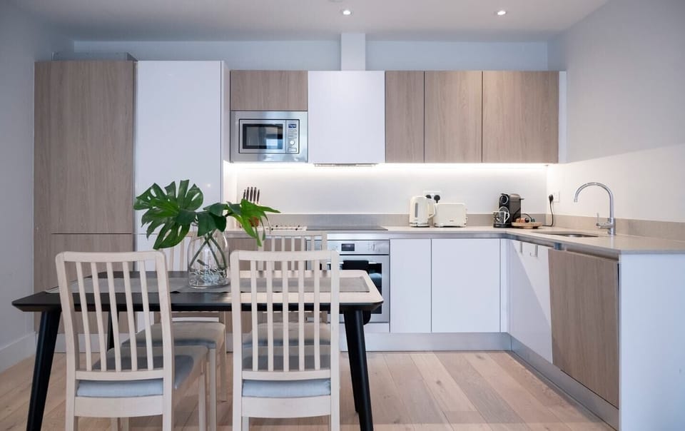 The fully equipped kitchen has an oven and induction hob, microwave, kettle, toaster, dishwasher, Nespresso machine, and a dining table with four chairs.