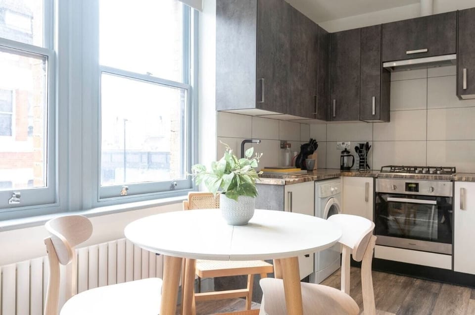 Open-plan living area with kitchen, sofa, TV, and workspace.