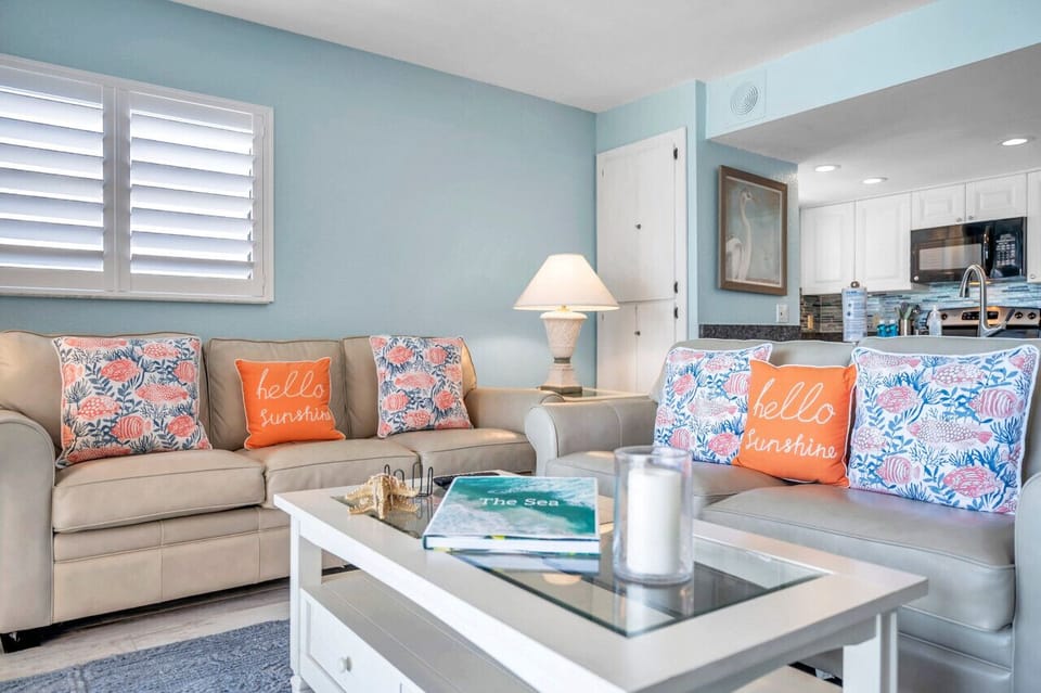 Cozy seating area w/ colorful accents & natural light streaming through plantation shutters.