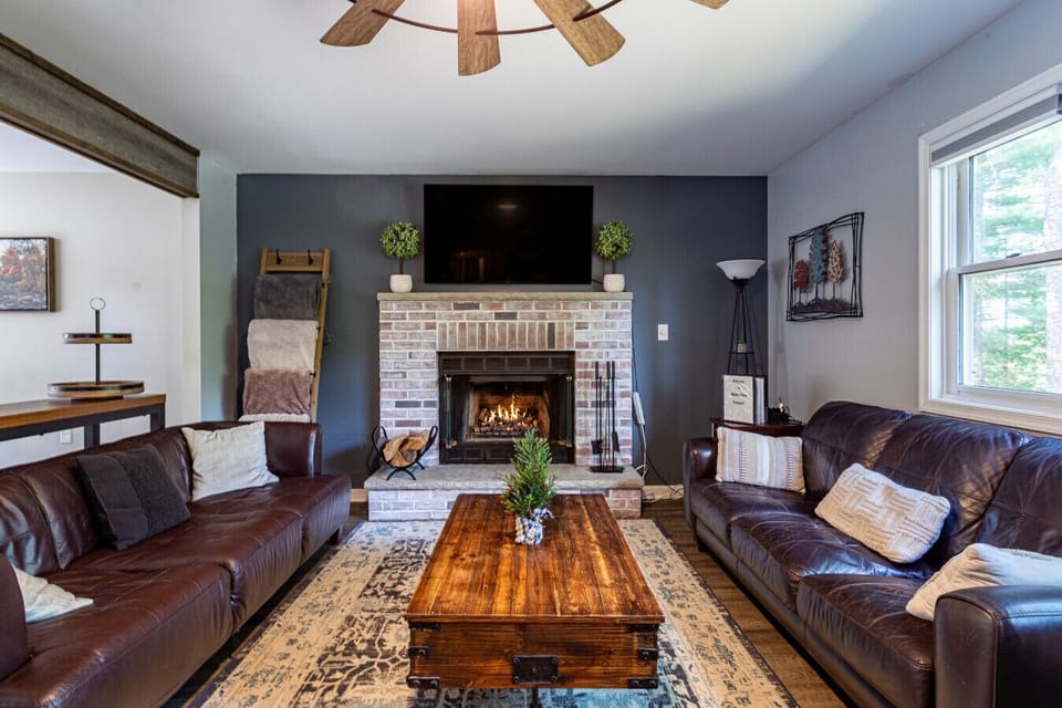 Warm and inviting living room with a brick fireplace, cozy leather seating, and stylish rustic accents.
