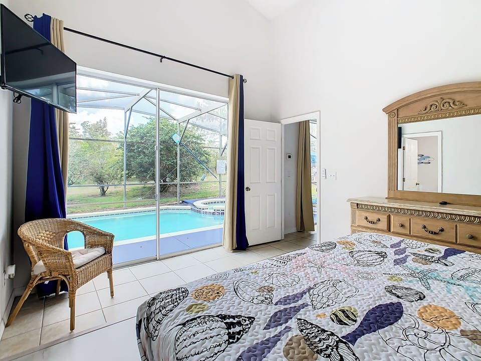 - Peaceful bedroom retreat with sliding doors that open straight to the pool and spa
- Elegant wicker chair and large dresser provide comfort and functional charm
- Enjoy a morning coffee or an evening swim just steps from your bed

