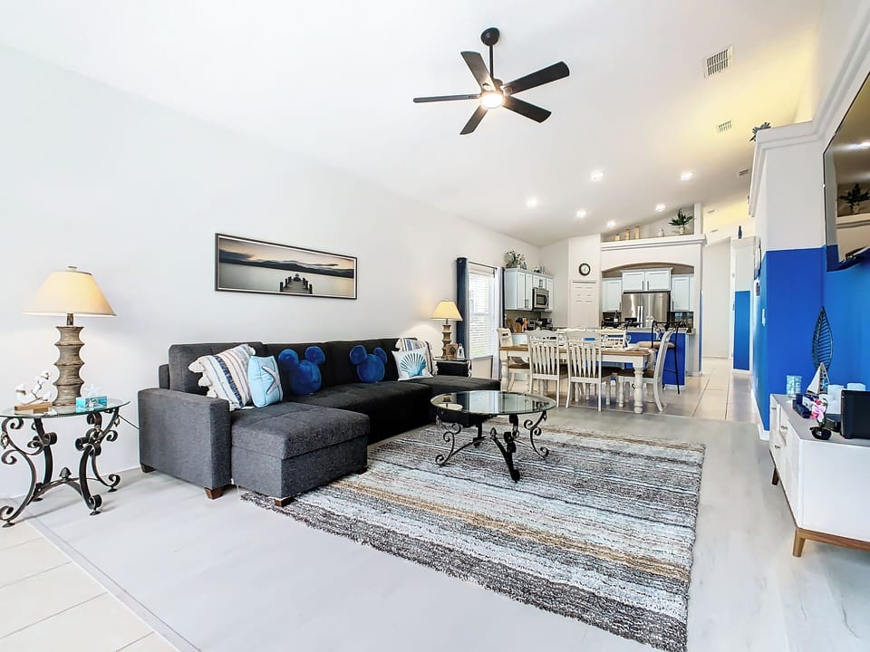 - Bright open concept living room with cozy sectional, coastal pillows, and Mickey accents
- Stylish mix of dark furnishings and crisp whites creates a clean, modern beachy feel
- Seamless flow to dining and kitchen areas makes it ideal for entertaining

