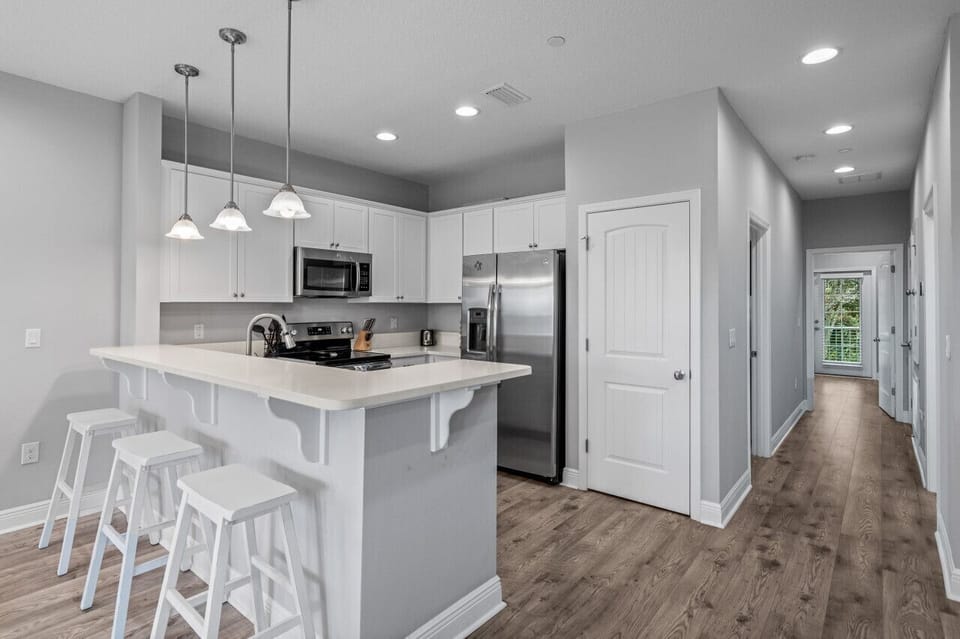 Your spacious kitchen features modern white cabinetry, stainless appliances, and a breakfast bar perfect for morning coffee or evening wine.