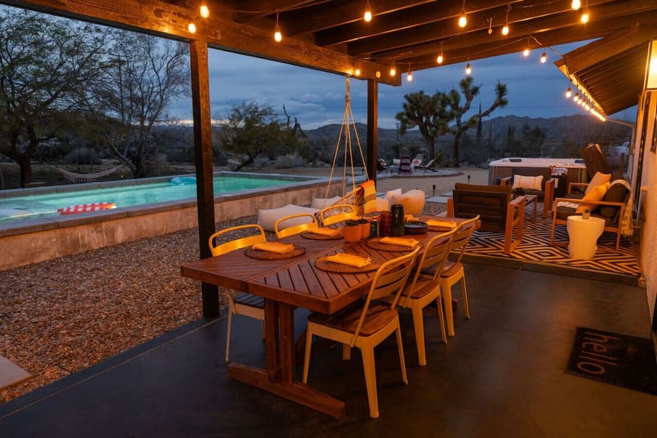 Dine under the stars without sitting in them — our covered outdoor dining area with string lights, lounge seating, and pool views makes every meal an occasion.