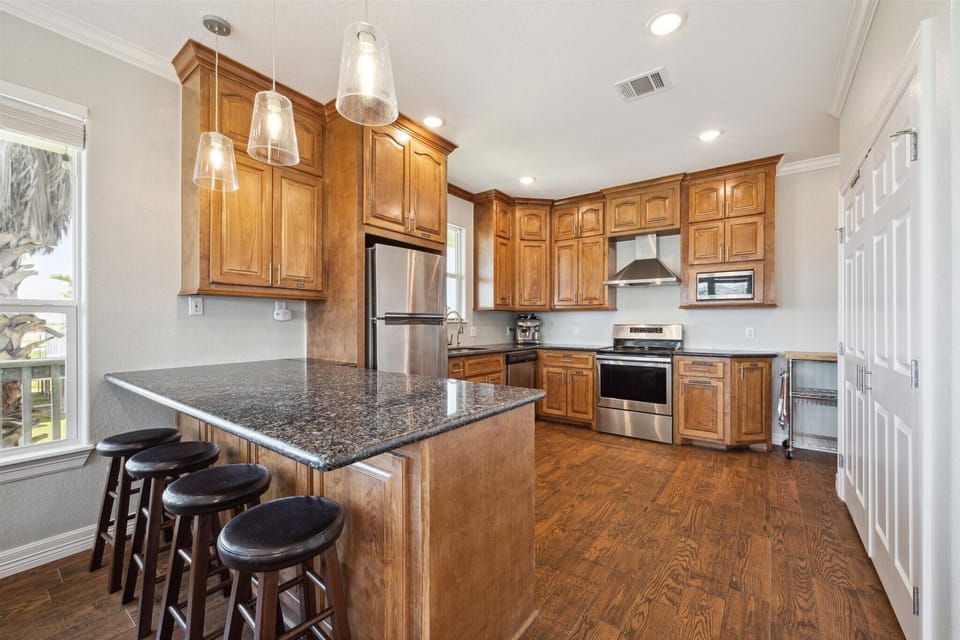 The kitchen features slab granite counters and bar seating with wood cabinetry and all stainless steel appliances.