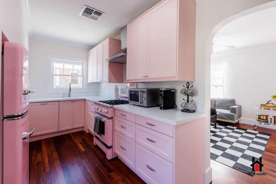 A pink retro kitchen, well equipped for preparing meals at home