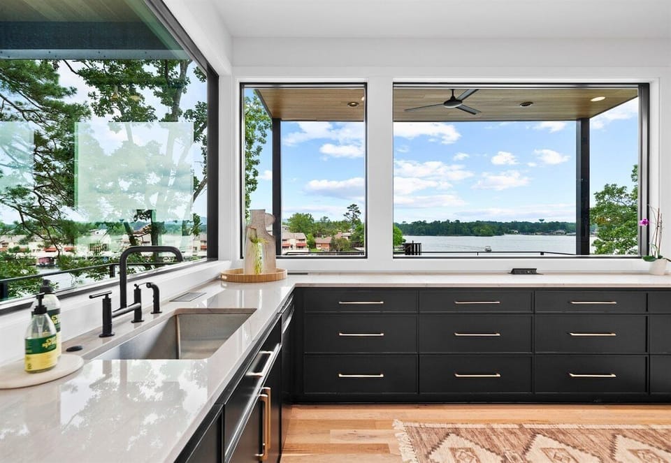 This kitchen's open layout and stylish decor make it the heart of the home. The combination of dark cabinetry and light wood floors creates a welcoming atmosphere.