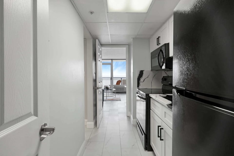 From morning coffee to midnight snacks, this sleek kitchen's got you covered—with ocean views peeking through the end of the hall, even cooking feels like a vacation.