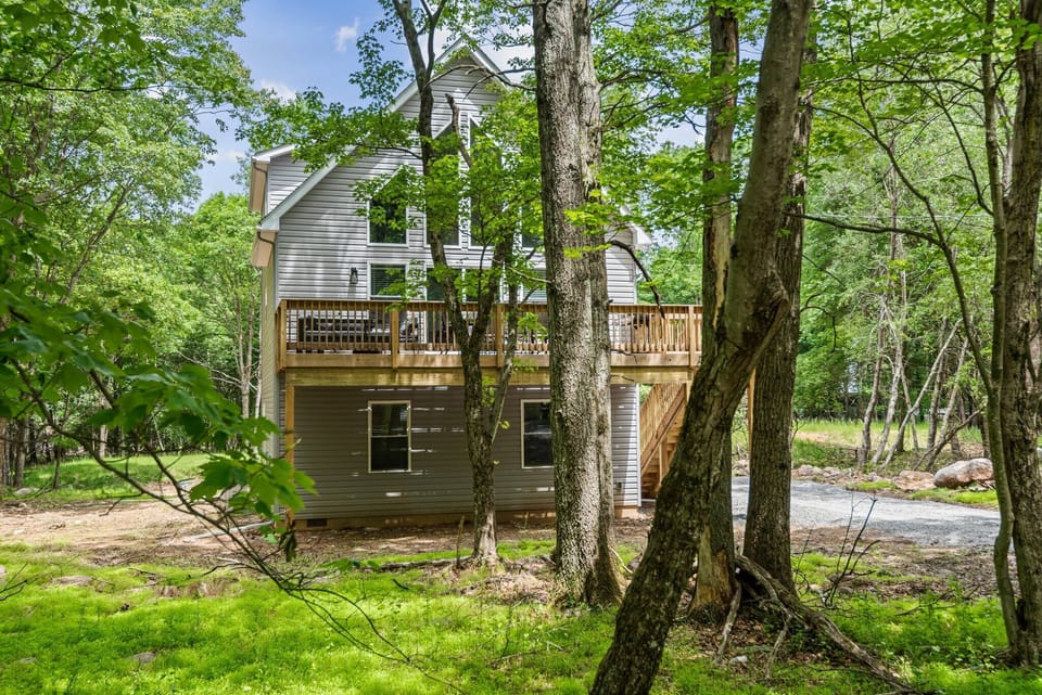 Nestled among tall trees, the rear view of the home shows off its peaceful vibe and the perfect blend of privacy and nature.