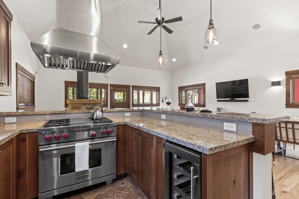 Town Lift Chalet's kitchen with breakfast bar, stainless steel Wolf range, stainless hood vent, and wine fridge.