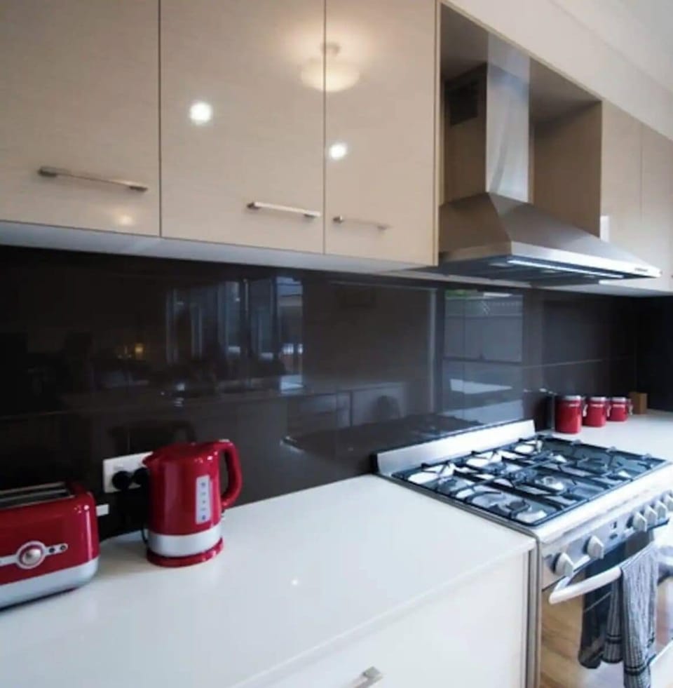 Kitchen with gas stove, oven, toaster, kettle, microwave, coffee pod machine.