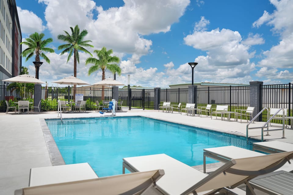 Dive into sunny poolside relaxation with loungers and palms.