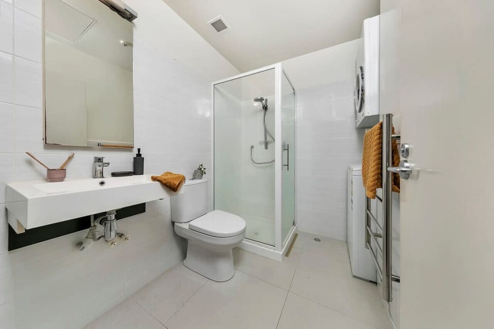 A spacious, modern bathroom with a walk-in shower, elegant white tiles, and essential amenities.