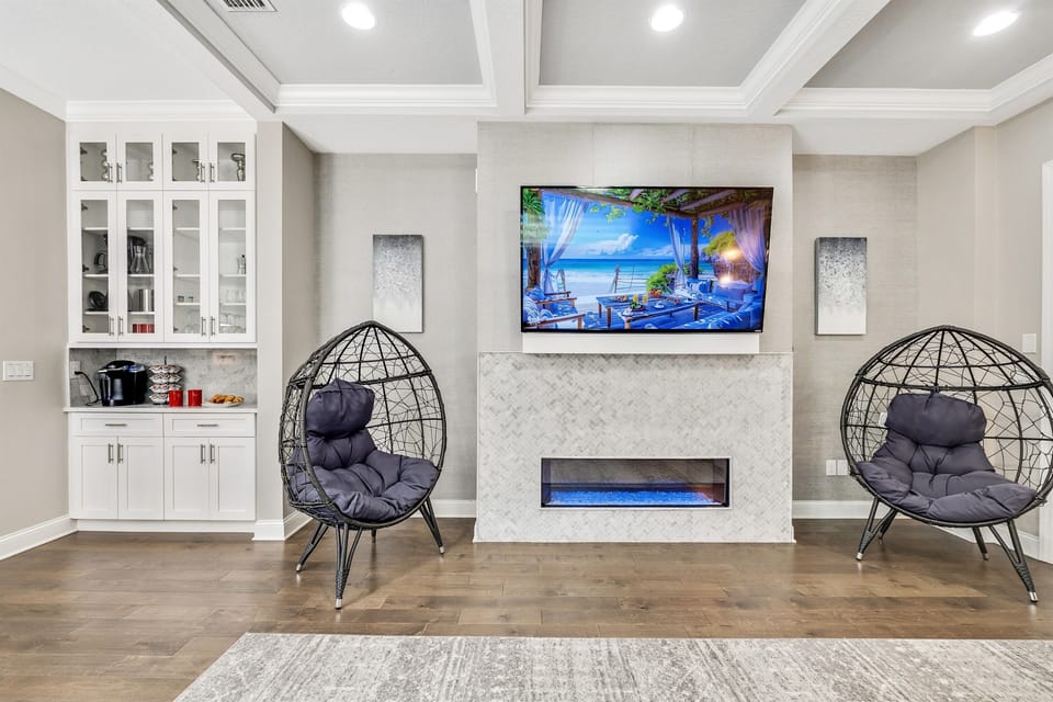 The room's warm wooden floors add a touch of rustic charm, enhancing the cozy atmosphere and providing a beautiful contrast to the plush furnishings.