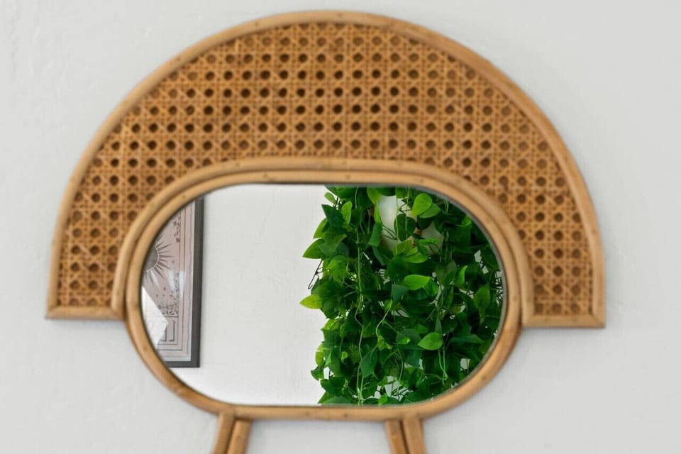 Arched woven mirror w/ trailing greenery adding texture and warmth to the space.