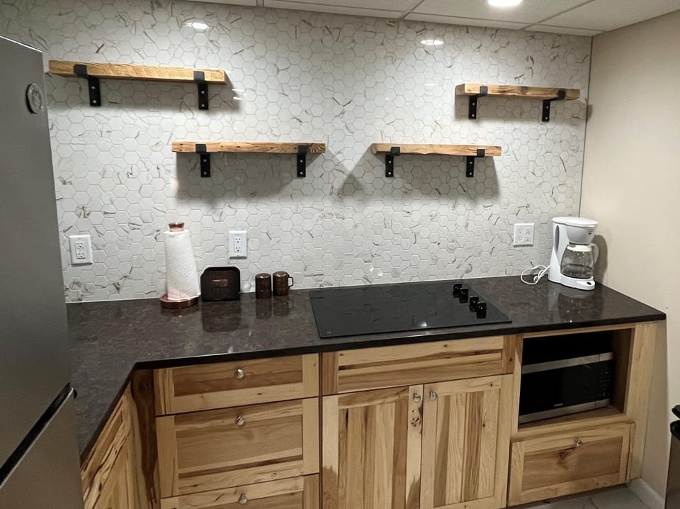 Kitchenette with custom backsplash and open shelves.