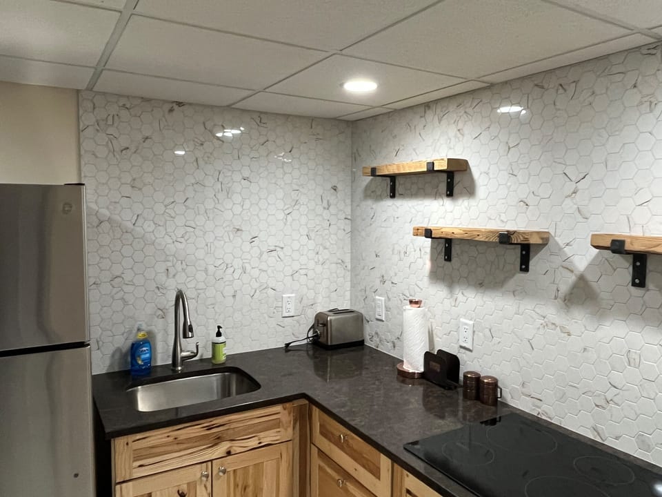Kitchenette with custom backsplash and open shelves.