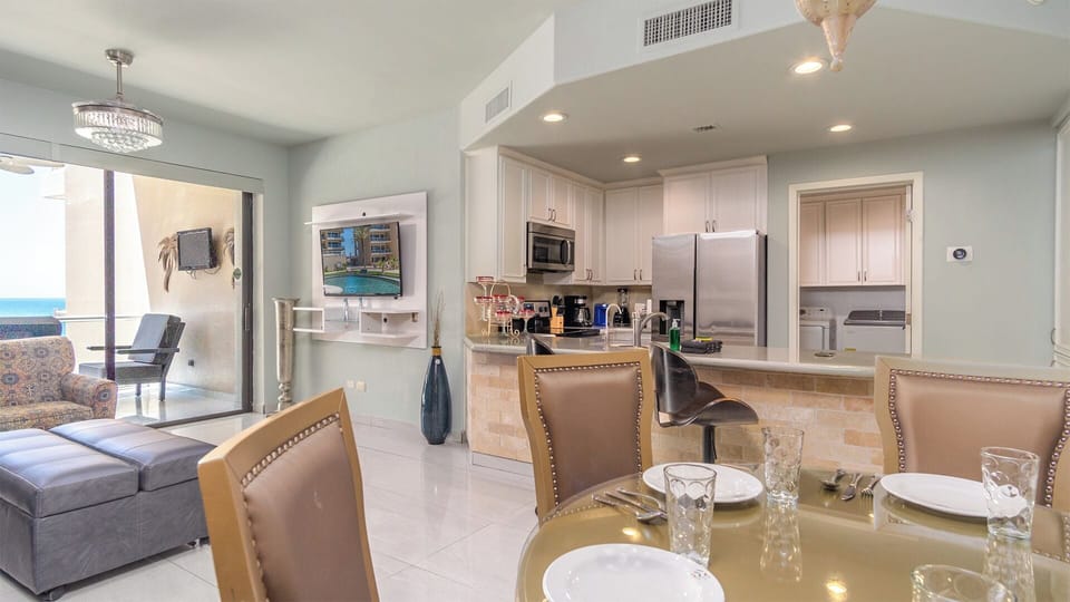 The dining table, living groom, and kitchen counter area.