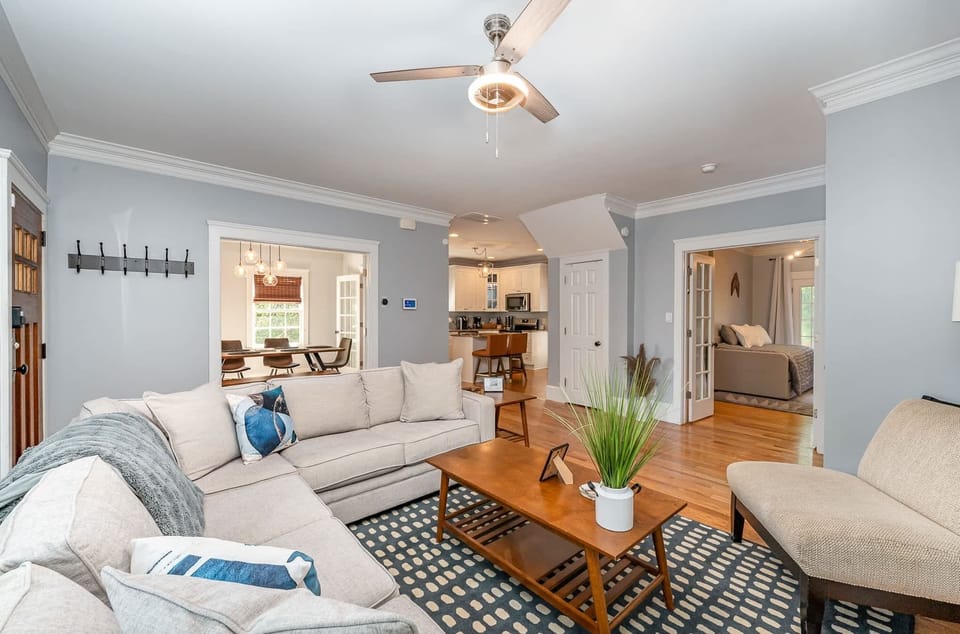 Discover our harmoniously designed living area, connecting a cozy sofa, entertainment-ready TV, seamless access to the dining room, kitchen amenities, and a cozy bedroom for a complete home experience.