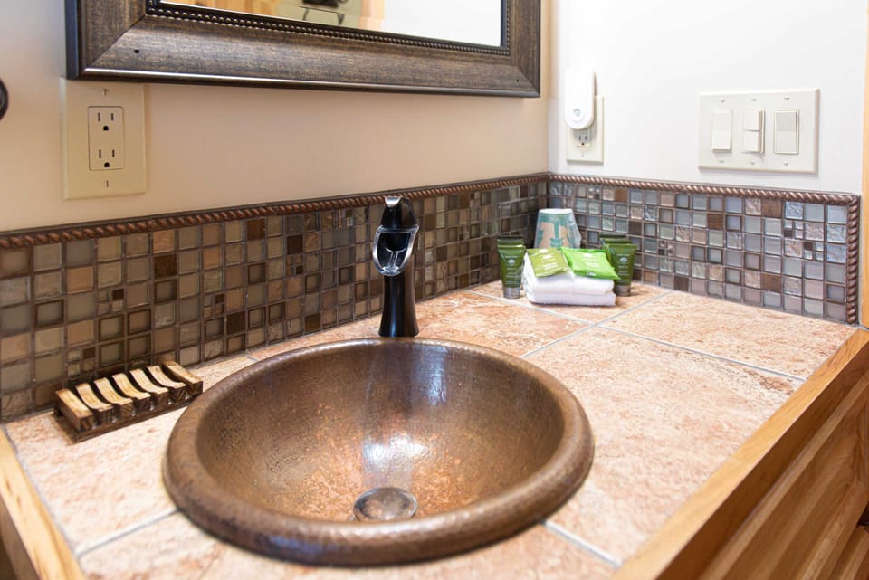 Penny copper sink, tiled countertop, surrounded with backsplash and luxerious hotel soaps.