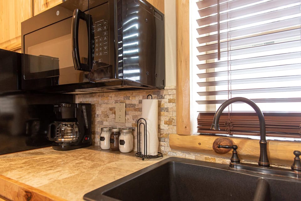 Double sink surrounded with hickory cabinets, luxurious tilework, and wood framed window.