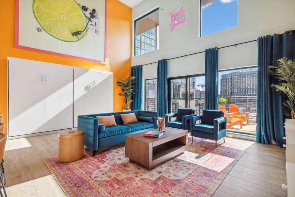 Bright open-concept living space with a Smart TV, queen Murphy beds, and a modern kitchen with bar seating—plus a private balcony right off the room for fresh air + skyline vibes!