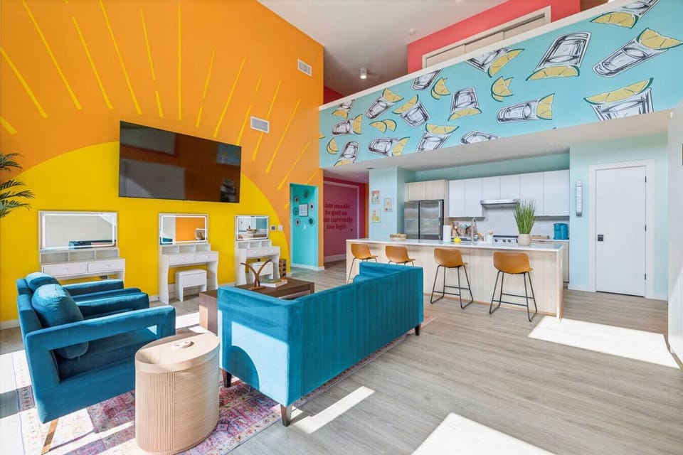 Bright open-concept living space with a Smart TV, queen Murphy beds, and a modern kitchen with bar seating—plus a private balcony right off the room for fresh air + skyline vibes!