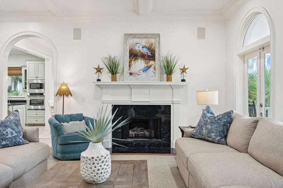 Sink into plush sofas by your elegant fireplace, where coastal artwork and soft lighting create the perfect atmosphere for relaxing evenings.