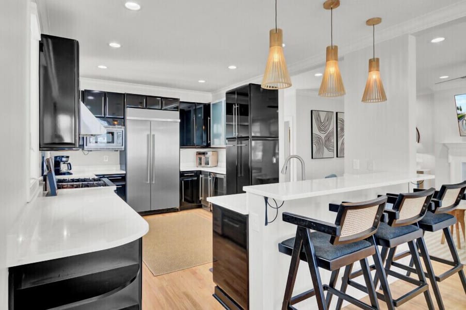 Your stylish open kitchen features sleek black cabinetry, premium appliances, and a bright breakfast bar where you can enjoy morning coffee together.