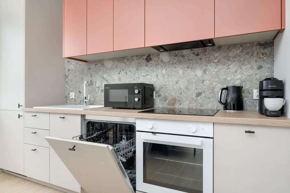 Fully equipped kitchen with coral cabinets
Contemporary kitchen with oven, hob, and coffee machine.

