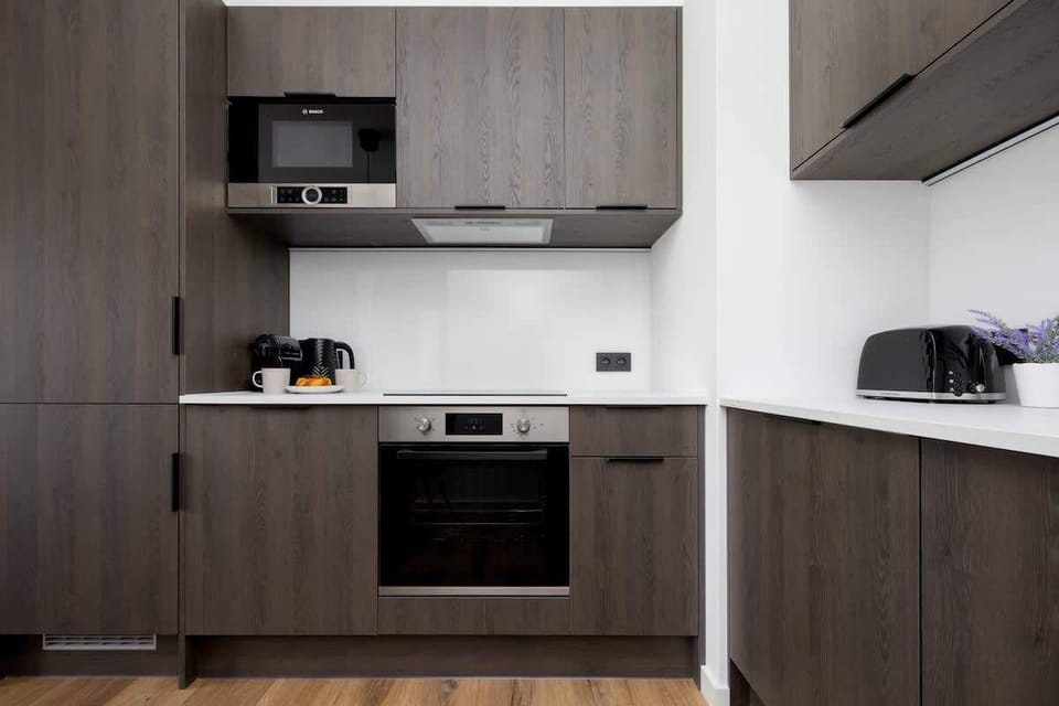 A compact kitchen with built-in appliances and sleek dark cabinetry.

