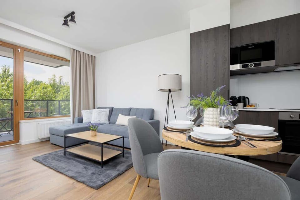 A well-lit living area with a comfortable sofa and a round table set for four.
