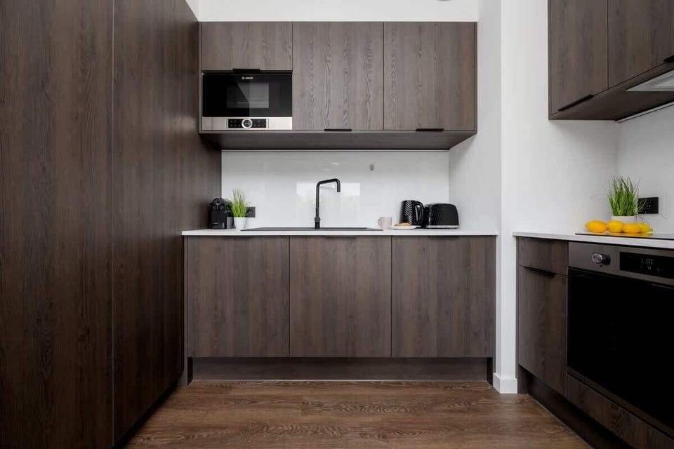 A compact kitchen with built-in appliances and sleek dark cabinetry.
