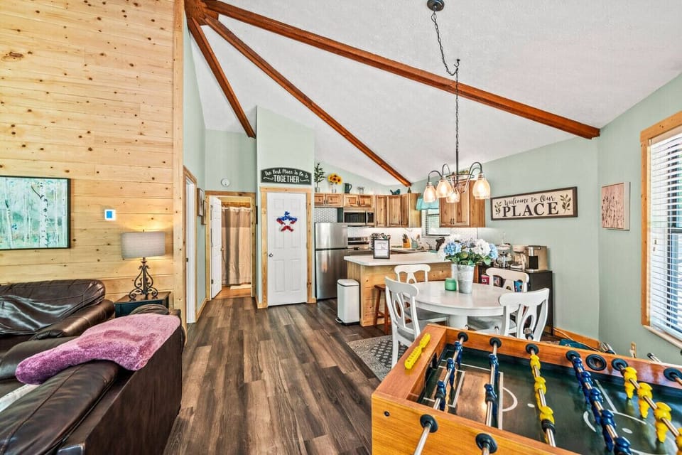 The main living area of the cabin includes the living room, a dining table, the kitchen, and a foosball table.