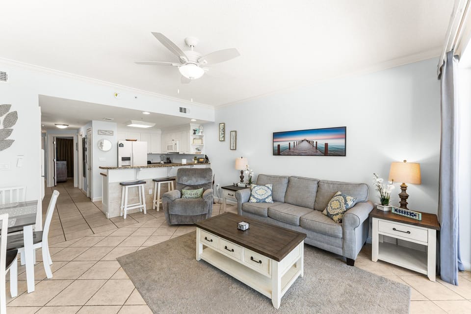 The living room offers ample, comfortable seating with expansive views of the Gulf of Mexico, a large flat screen television, and access to the unit's private balcony.