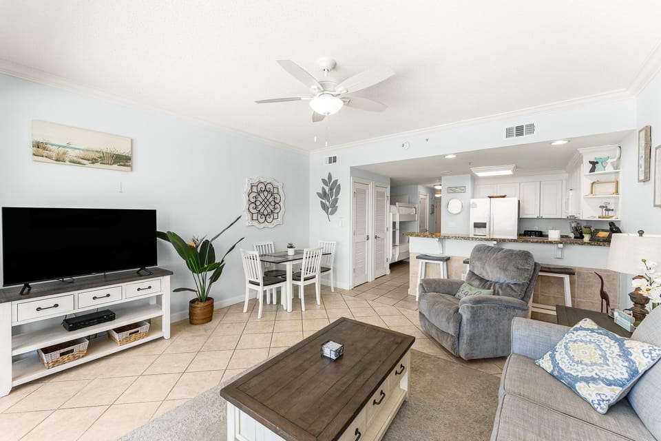 The living room offers ample, comfortable seating with expansive views of the Gulf of Mexico, a large flat screen television, and access to the unit's private balcony.