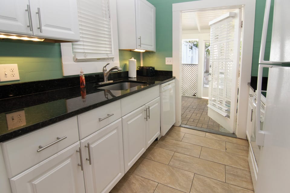 Kitchen with back door that opens up to a private screened in covered patio with seating