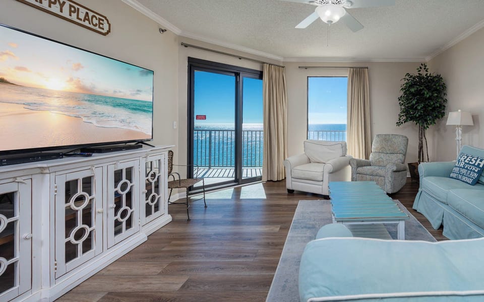 Relax in the inviting living area with comfortable seating, a large TV, and beautiful views through expansive windows