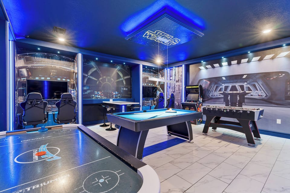 Step into this vibrant game room where bright blue accents and dynamic wall art create an exciting atmosphere. Enjoy friendly competition at the sleek pool table or air hockey setup, illuminated by stylish overhead lighting.