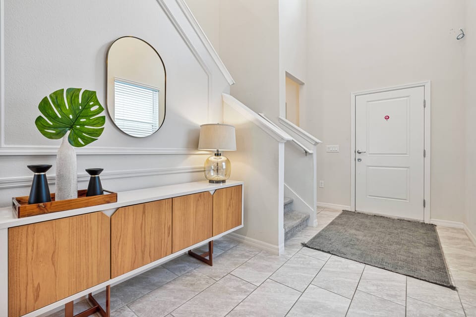 Step into this airy entryway, featuring a sleek wooden sideboard complemented by a stylish lamp and decorative accents. The neutral color palette and natural light create a warm welcome, setting the tone for your stay.