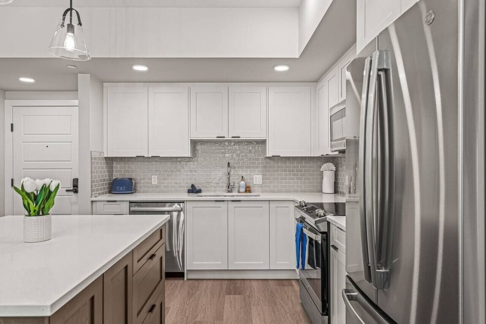 Fabulous, ultra-modern kitchen with all white cabinets, white quartz countertops, and an oversized kitchen island